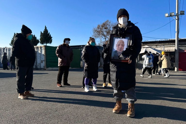 A family member carries the photo of a deceased relative outside a crematorium in Beijing, Saturday, Dec. 17, 2022. 