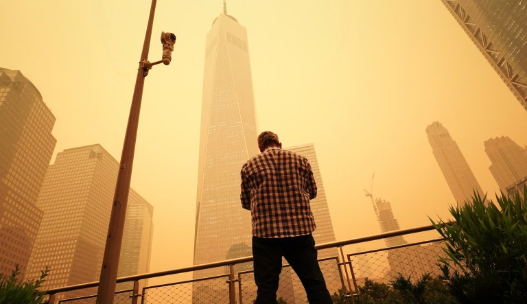 A man pauses to look at the smoke and haze shrouding One World Trade Center building in New York City, Wednesday, June 7, 2023. Intense Canadian wildfires are blanketing the northeastern U.S. in a haze, turning the air acrid and the sky yellowish gray.