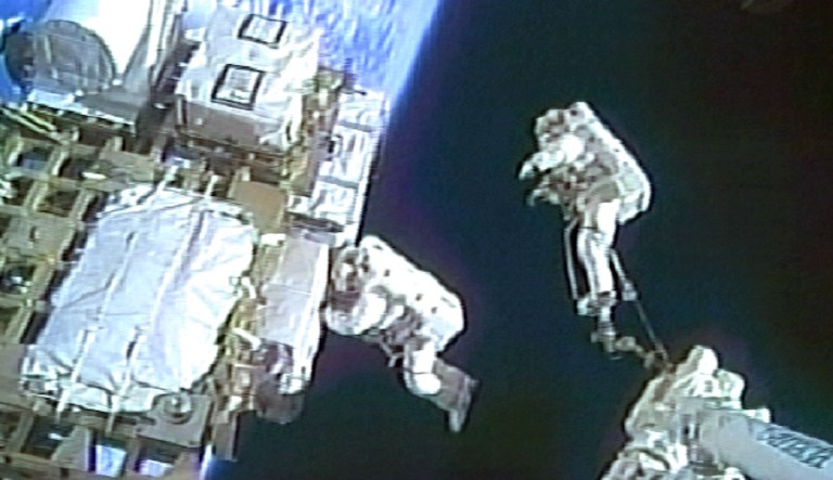 In this image from NASA television,  Endeavour astronauts David Wolf, right, and Thomas Marshburn float above Earth as they work on attaching spare parts to the space station during a spacewalk Monday, July 20, 2009.