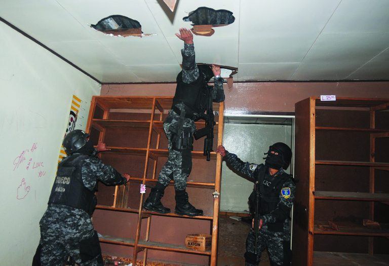 In this June 14, 2012 photo, national police inspect a home that had been seized by gangs in the 14 de Marzo neighborhood in Tegucigalpa, Honduras. Gang members seized the home after the rightful owners fled, unable to pay their extortion fees. Extortion of homeowners is a chilling new crime trend in Honduras, already among the world's most dangerous countries. By demanding people pay to stay in their own homes, gang members have emptied some neighborhoods and have changed the way many live. (AP Photo/Fernando Antonio)