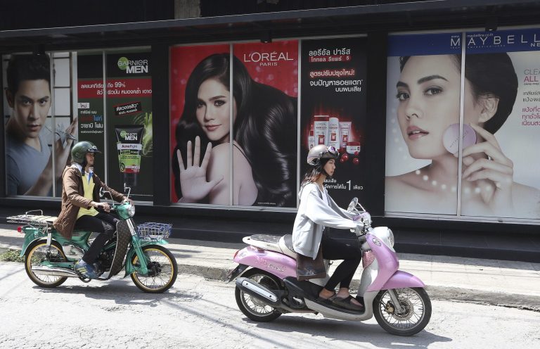 Two motorcyclists ride past cosmetic advertisement signs in downtown Chiang Mai, northern Thailand, Monday, May 19, 2014. Thailand's economy contracted by 2.1 percent in the first quarter, slammed by a protracted political crisis that is likely to slow growth for the rest of the year. (AP PhotoApichart Weerawong)