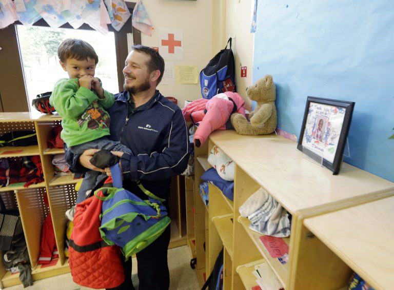 In this Sept. 18, 2014 photo, Jason Prosser picks up his son Zachary, 3, from day care, in SeaTac, Wash. Prosser and his wife are one of many middle-class couples struggling with accelerating costs for critical services such as health care and housing. At the same time, their income has been stagnant for the past three years. (AP Photo/Ted S. Warren)