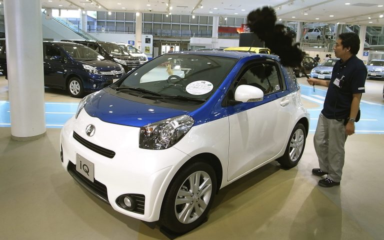 A worker cleans an IQ compact car at a Toyota showroom in Tokyo, Wednesday, July 30, 2014. Toyota remains No. 1 in global vehicles sales after the first six months of this year, followed by Volkswagen which bumped General Motors out of second place as the U.S. automaker grapples with a recall scandal. (AP Photo/Eugene Hoshiko)