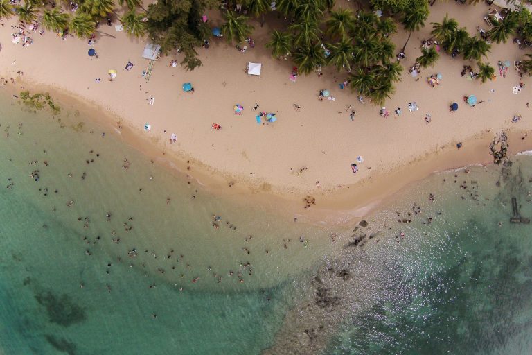 This July 16, 2014, photo, shows an aerial view of people enjoying the beach in San Juan, Puerto Rico. The territory's government has managed its first balanced budget in more than a decade. Sales tax revenues are up and its publicly owned power company has won breathing room to pay its debts. (AP Photo/Ricardo Arduengo)