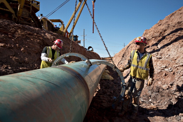 Workers remove a large clamp from a section of pipe during construction of the Gulf Coast Project pipeline in Prague, Oklahoma, U.S., on Monday, March 11, 2013. The Gulf Coast Project, a 485-mile crude oil pipeline being constructed by TransCanada Corp., is part of the Keystone XL Pipeline Project and will run from Cushing, Oklahoma to Nederland, Texas. (Daniel Acker/Bloomberg via Getty images)