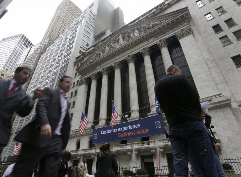In this Oct. 2, 2014 photo, people pass the New York Stock Exchange, in New York. Stocks are opening mostly lower Monday, Oct. 20, 2014, as traders look over some disappointing corporate results. (AP Photo/Richard Drew)