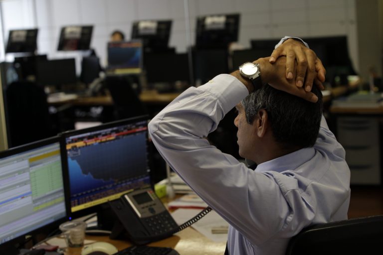 A broker stretches as he talks on the phone in a trading room of a Portuguese bank in Lisbon, Thursday, July 10, 2014. Share prices on the Lisbon stock exchange fell more than 4 percent and Portugal's bond yields ticked higher amid growing concern about the health of one of the country's largest financial groups. (AP Photo/Francisco Seco)