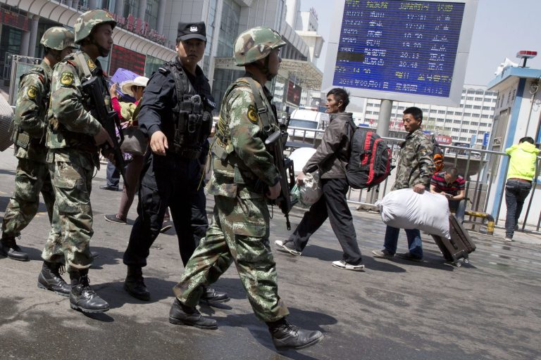Heavily armed Chinese paramilitary policemen march past the site of the explosion outside the Urumqi South Railway Station in Urumqi in northwest China's Xinjiang Uygur Autonomous Region Thursday, May 1, 2014. Chinese President Xi Jinping has demanded "decisive actions" against terrorism following the attack at the railway station in the far west minority region of Xinjiang that left three people dead and 79 injured.