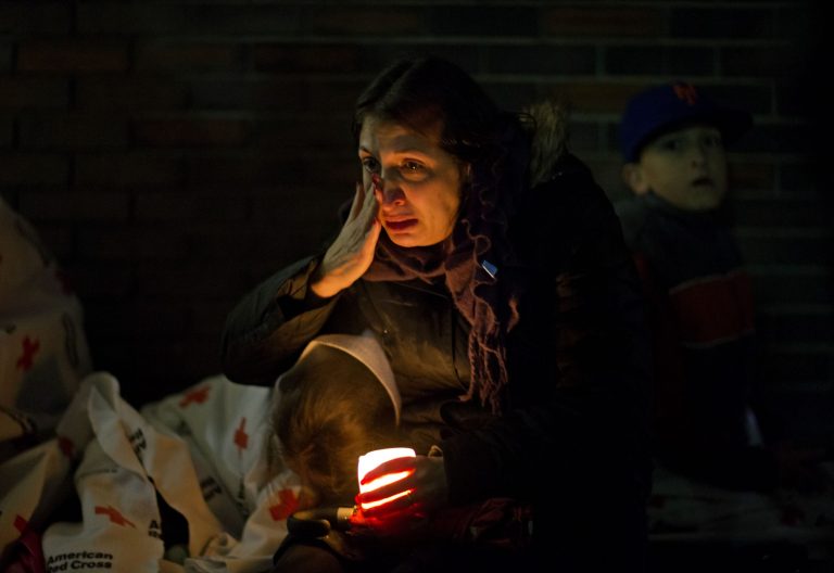   A mourner weeps while listening to President Barack Obama speak on a loudspeaker while sitting outside a memorial at Newtown High School for the victims of the Sandy Hook Elementary School shooting, Sunday, Dec. 16, 2012, in Newtown, Conn. (AP Photo/David Goldman)  