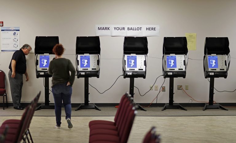 In this Thursday, Oct. 19, 2017 photo, Kelly Monroe, investigator with the Georgia secretary of state office, left, takes a look at a new voting machine being tested at a polling site in Conyers, Ga. Last summer, a security expert came across a gaping hole in Georgia's election management system.