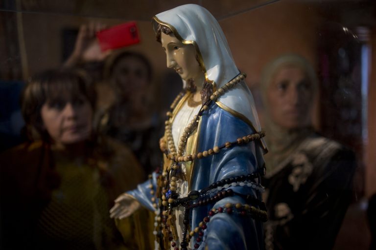Christian worshipers gather next to a statue of the Virgin Mary, that residents say "weeps" oil, inside an apartment belonging to the Khoury family, in Tarshiha, a small town in northern Israel,Tuesday, Feb. 11, 2014. The family says it is most striking when a "tear" seems to roll down the statue's cheek. It says some 2,000 people have come to see the statue over the last week.