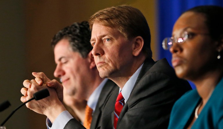 FILE - In this Thursday, March 26, 2015, file photo, Consumer Financial Protection Bureau Director Richard Cordray, center, listens to comments during a panel discussion in Richmond, Va. (AP Photo/Steve Helber, File)