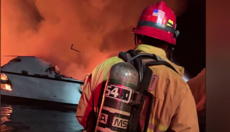 Firefighters work to put out a fire on a boat off the coast of California