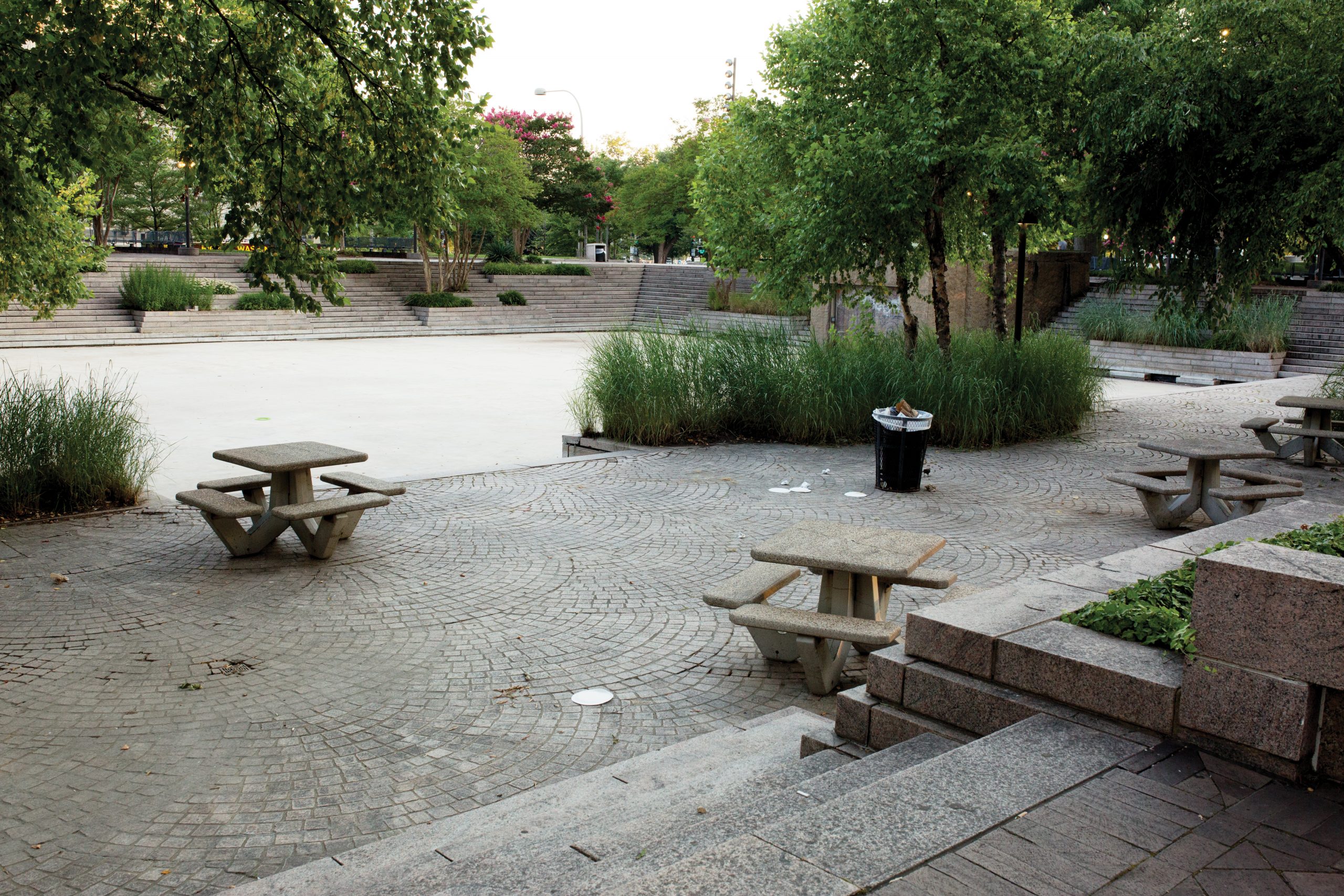 Pershing Park as it looks today: Ugly tables hunch near the empty pool, enclosed on two sides by granite steps and planters.