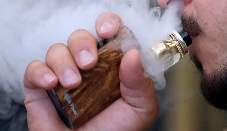 A man breathes vape from an e-cigarette at a vape shop in London, Friday, Aug. 17, 2018.