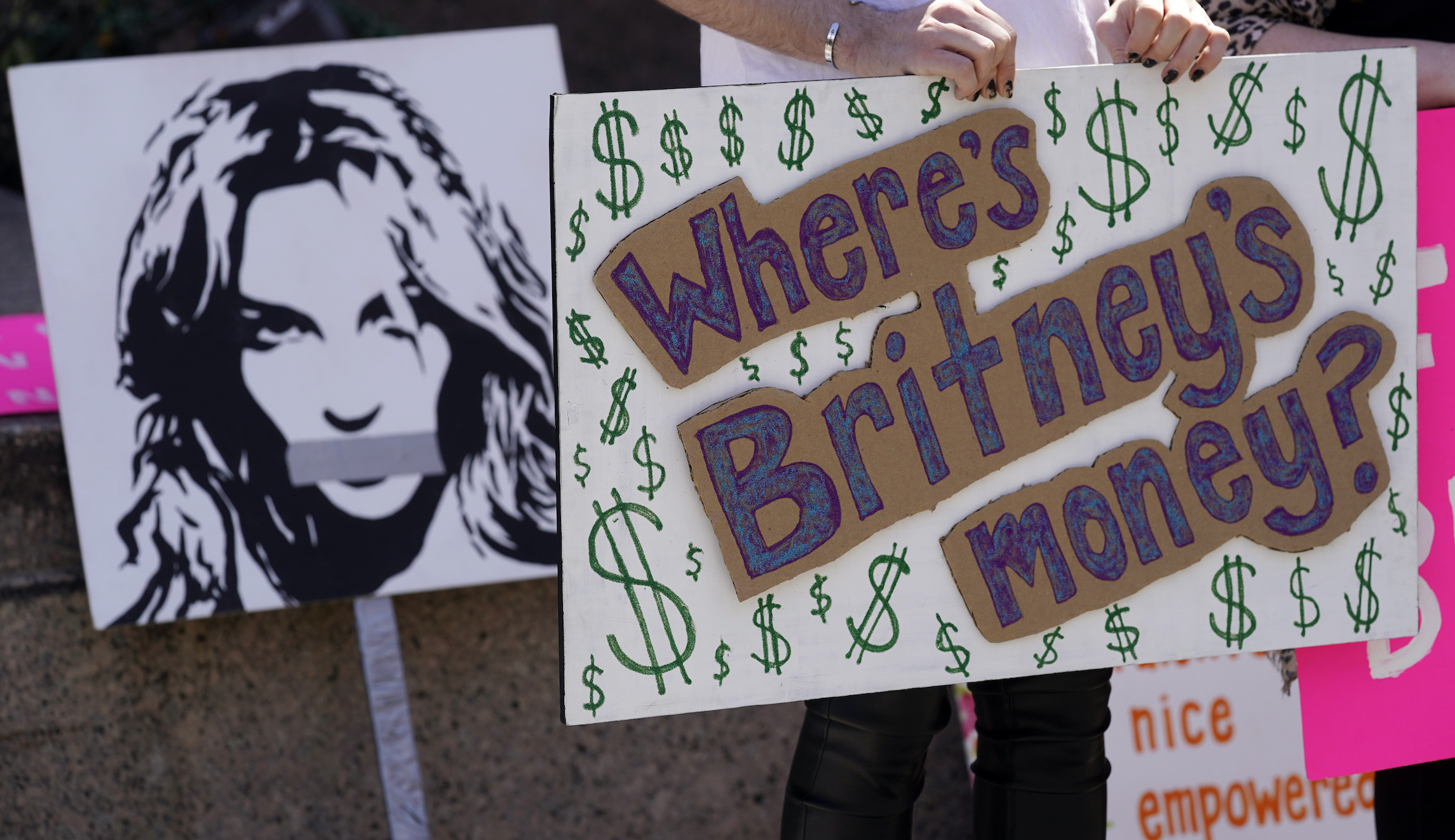 A Britney Spears supporter holds a sign near a portrait of her outside a court hearing concerning the pop singer's conservatorship at the Stanley Mosk Courthouse on March 17 in Los Angeles. Attorneys for Spears and lawyers for her father Jamie Spears jointly asked the judge to delay an accounting and status report on the conservatorship until April 27.
