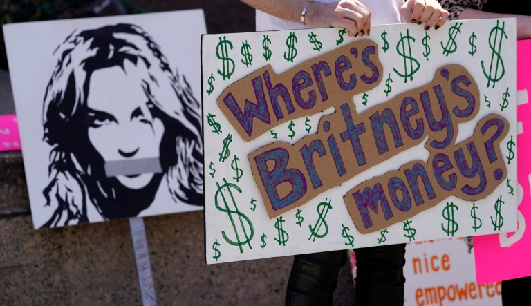 A Britney Spears supporter holds a sign near a portrait of her outside a court hearing concerning the pop singer's conservatorship at the Stanley Mosk Courthouse on March 17 in Los Angeles. Attorneys for Spears and lawyers for her father Jamie Spears jointly asked the judge to delay an accounting and status report on the conservatorship until April 27.