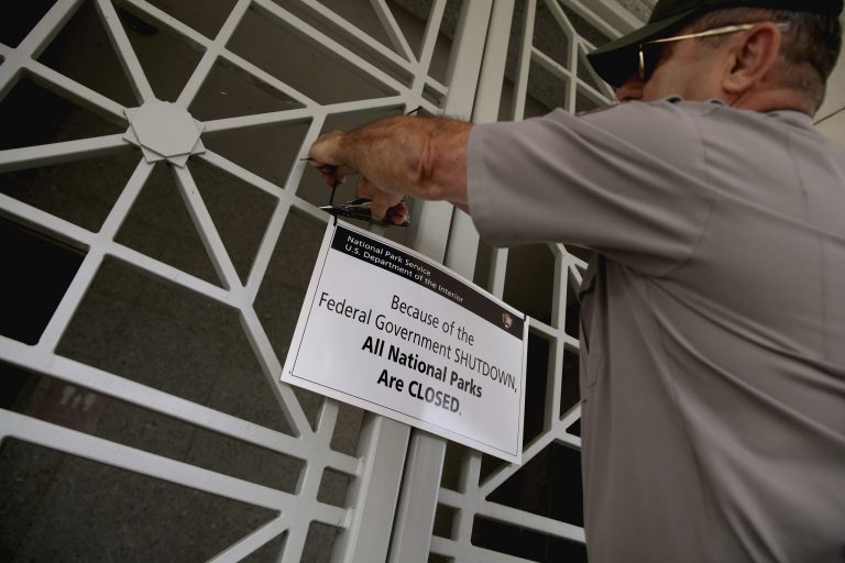 U.S. Park Service employee puts a closed sign on the restrooms at the World War II Memorial ticket office on the National Mall on Oct. 1, 2013, in Washington. (Photo by Chip Somodevilla/Getty images)