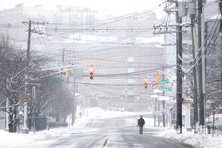 A pedestrian walks on a snow covered road after an overnight snowstorm Tuesday in Hoboken, N.J. (AP/Julio Cortez)