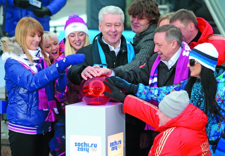 Moscow's Mayor Sergei Sobyanin, center, surrounded by various officials, sport enthusiasts and entertainers hits a symbolic button to launch the one-year count down clock for the upcoming 2014 Sochi Olympics, in Moscow, Russia, Thursday, Feb. 7, 2013. (AP Photo/Mikhail Metzel)