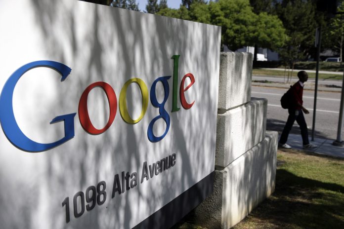 FILE - In this June 5, 2014 file photo, a man walks past a Google sign at the company's headquarters in Mountain View, Calif. Google reports quarterly financial results after the market closes Thursday, Oct. 16, 2014. (AP Photo/Marcio Jose Sanchez, File)