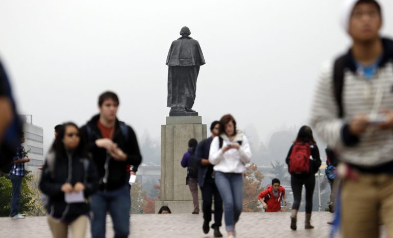 University of Washington students walk past a statue of George Washington that towers near a west entrance on the campus in Seattle. (AP/Elaine Thompson)
