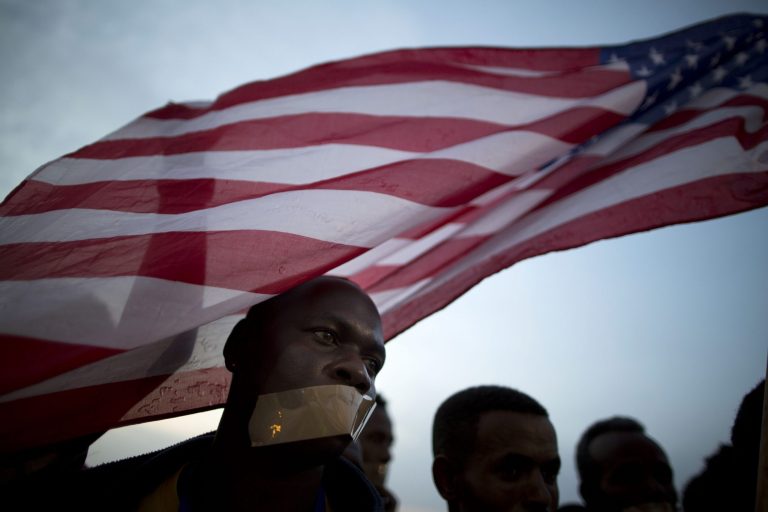 An African migrant covers his mouth with tape during a protest in front of the U.S. embassy demanding asylum and work rights from the Israeli government in Tel Aviv, Israel, Wednesday, Jan. 22, 2014. About 60,000 African migrants, mostly from Sudan and Eritrea, have trekked through Egypt and other Muslim countries to reach Israel in recent years. Some are fleeing violence or oppression in their home countries while others are seeking better economic opportunities in Israel. (AP Photo/Oded Balilty)