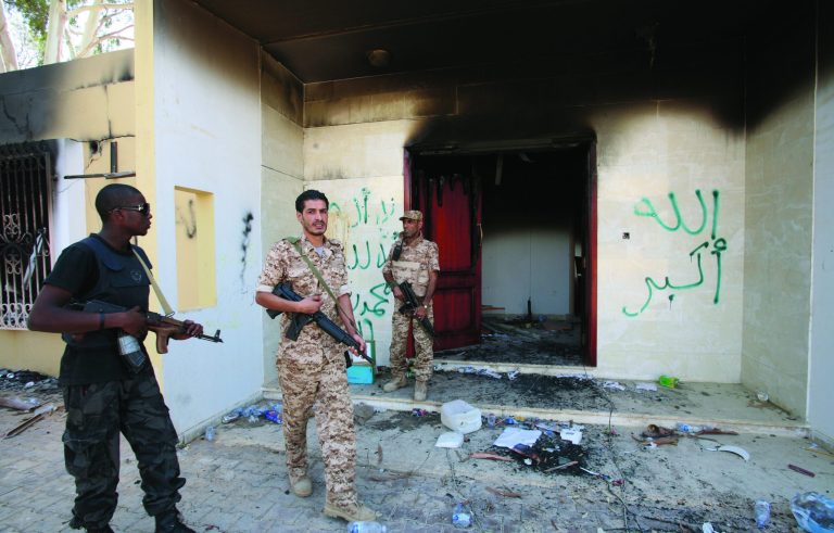 FILE - In this Friday, Sept. 14, 2012 file photo, Libyan military guards check one of the U.S. Consulate's burnt out buildings during a visit by Libyan President Mohammed el-Megarif, not shown, to the U.S. Consulate to express sympathy for the death of the American ambassador, Chris Stevens and his colleagues in the deadly attack on the Consulate last Tuesday, September 11, in Benghazi, Libya. Britain's Foreign Office urged U.K. nationals to immediately leave the eastern Libyan city of Benghazi in response to an imminent threat against Westerners. The Arabic on the building reads, 