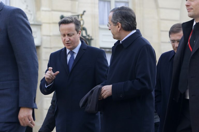 British Prime Minister David Cameron, left, and Greek Prime Minister Antonis Samaras speak as they leave the Elysee Palace to board a bus to join a rally, in Paris, Sunday Jan. 11, 2015. A rally of defiance and sorrow, protected by an unparalleled level of security, on Sunday will honor the 17 victims of three days of bloodshed in Paris that left France on alert for more violence. (AP Photo/Thibault Camus)
