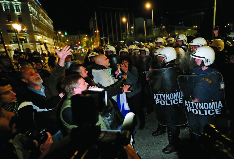Greek riot police officers, right, push the last remaining protesters off the street, following an anti-austerity rally in front of the Parliament in central Athens, Sunday, Nov. 11, 2012. Thousands of protesters converged on the Greek capital's main square outside the Parliament on Sunday evening, as lawmakers debated the 2013 budget, which includes pension and salary cuts demanded by the country's international creditors in order for them to approve the next vital batch of rescue loans. (AP Photo/Lefteris Pitarakis)