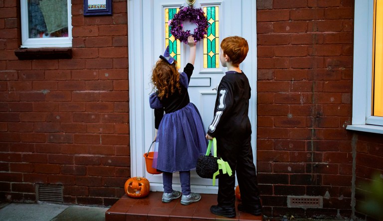 Two children dressed up to go trick-or-treating for Halloween.