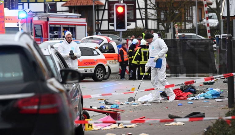 Police and rescue workers stand next to the scene of the accident with a car that is said to have crashed into a carnival parade in Volkmarsen, central Germany, Monday, Feb. 24, 2020. Several people have been injured, according to the police. The driver had been arrested by the police.