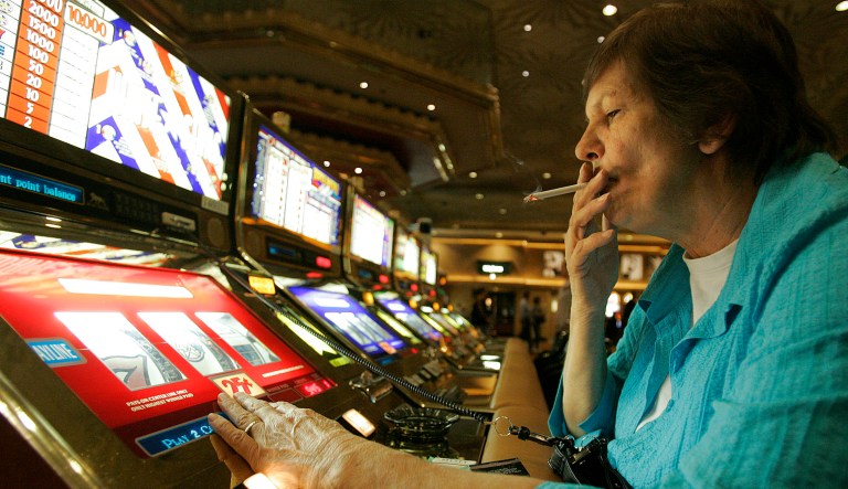 FILE - In this Dec. 28, 2005, file photo, Judy King of Daytona Beach, Fla., holds her cigarette while playing a slot machine at the MGM Grand hotel-casino in Las Vegas. One of the last Las Vegas Strip resorts to reopen after coronavirus closures will be the first to be smoke-free, MGM Resorts International announced Monday, Sept. 14, 2020. Park MGM will prohibit tobacco smoke inside when it opens Sept. 30, said Anton Nikodemus, president and chief operating officer of the 3,000-room property that many remember as the Monte Carlo casino-hotel.