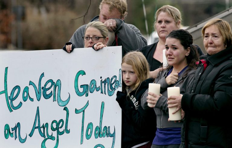   Tom Doyle, back left, standing with family and co-workers, wipes his face as the funeral procession for 6-year-old James Mattioli, who died in the Sandy Hook Elementary School shootings, approaches the St. John's Cemetery Tuesday, Dec. 18, 2012, in Darien, Conn. Center are his wife Debbie and daughter Emily, 10. Adam Lanza opened fire at the Sandy Hook Elementary School in Newtown on Friday, killing 26 people, including 20 children. (AP Photo/Craig Ruttle)  