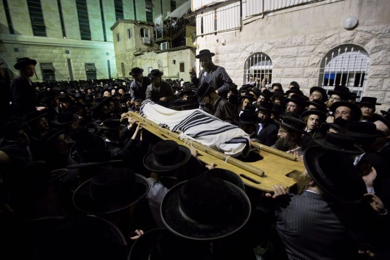 An ultra-Orthodox Jewish man carries the body of Avrohom Wallis during his funeral in Jerusalem, Monday, Aug. 4, 2014. An assault carried out with a construction vehicle served as another reminder of the tense climate. Israeli TV stations broadcast a series of amateur videos of the attack, in which a Palestinian man used the front shovel of a construction excavator to ram a bus and tip it over. Police said a man who worked at the site was run over and killed by the construction vehicle. He was identified as a 29-year-old religious inspector whose job was to ensure that ancient graves were not damaged by construction work. A policeman who happened to be in the area shot the driver, who was identified as a resident of a Palestinian neighborhood in east Jerusalem. The man's uncle, Hisham Jaabis, said the incident was a traffic accident and that his nephew had been gunned down in cold blood while trying to dodge the bus. 