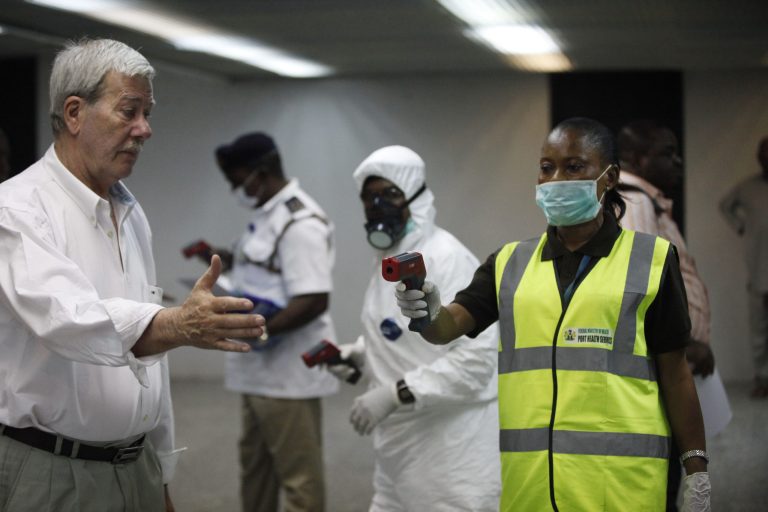Nigerian port health officials uses a thermometer on a worker at the arrivals hall of Murtala Muhammed International Airport in Lagos, Nigeria,  Wednesday, Aug. 6, 2014. A Nigerian nurse who treated a man with Ebola is now dead and five others are sick with one of the world's most virulent diseases, authorities said Wednesday as the death toll rose to at least 932 people in four West African countries. (AP Photo/Sunday Alamba)