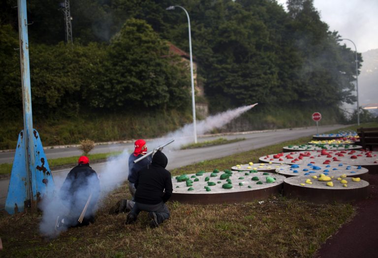   Miners fire handmade rockets at riot police officers as they defend their position near the mine 