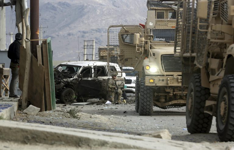 A U.S. army soldier, center, takes his position at the site of a suicide attack in Kabul, Afghanistan, Monday, Oct. 13, 2014. An Afghan official said a suicide bomber targeting a NATO convoy in Kabul killed one civilian and wounded three others. (AP Photo/Massoud Hossaini)