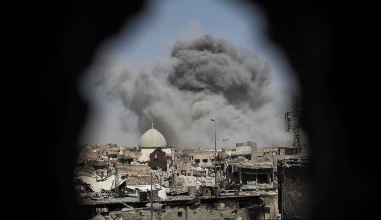 A bomb explodes behind the al-Nuri mosque complex, as seen through a hole in the wall of a house, as Iraqi Special Forces move toward Islamic State militant positions in the Old City of Mosul, Iraq, Thursday, June 29, 2017. (AP Photo/Felipe Dana)