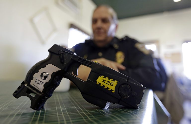 In this Nov. 14, 2013 photo, a Taser X26 is shown as Knightstown Police Chief Danny Baker talks about being shot by the weapon to raise money for his department in Knightstown, Ind. Baker is trying to raise money to lease a new car for the department by agreeing to be shot with his Taser.  (AP Photo/Michael Conroy)