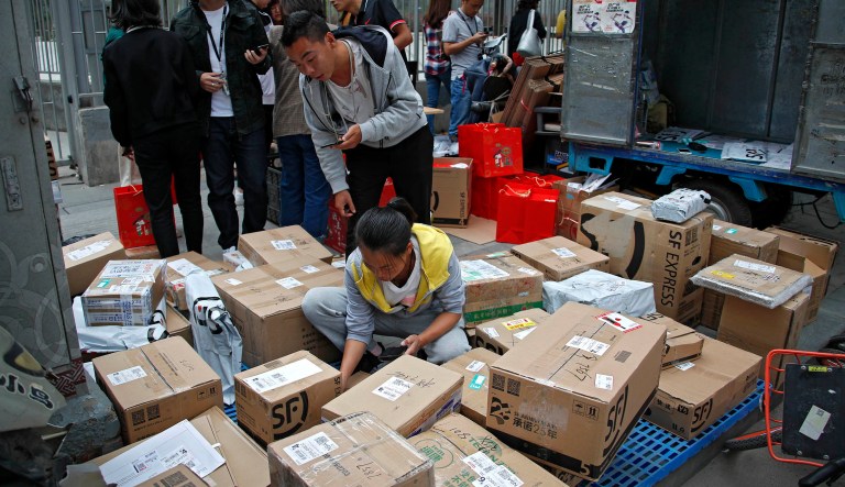 Delivery workers sort boxes of goods for their customers outside an office building in Beijing, Wednesday, Sept. 19, 2018.