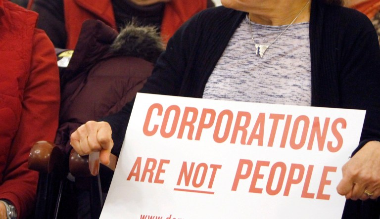 In this Jan. 20, 2012  photo, people hold signs during a gathering on the anniversary of the Citizens United decision in Montpelier, Vt. First, it was the Vermont senator with socialist leanings. Then it was Jerry of Ben & Jerry's ice cream fame. Now there are about 50 Vermont communities ready to chime in on a proposal to pass a Constitutional amendment to clarify that corporations do not have the same rights as human beings.,