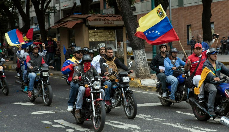 Supporters of President Nicolas Maduro known as "Colectivos", parade in on their motorbikes while anti=government supporters take part in a walkout against Maduro, in Caracas, Wednesday, Jan. 30, 2019. Venezuelans are exiting their homes and workplaces in a walkout organized by the opposition to demand that Maduro leave power.