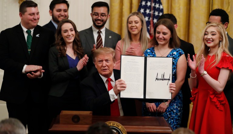 President Donald Trump holds up an executive order requiring colleges to certify that their policies support free speech as a condition of receiving federal research grants, after signing, Thursday March 21, 2019, in the East Room of the White House in Washington.