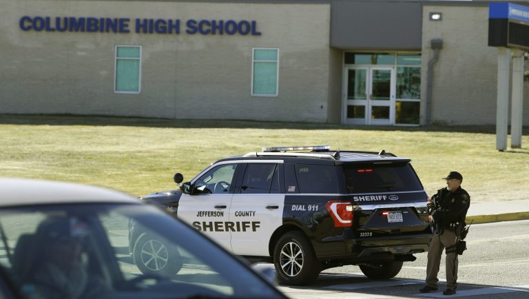 A member of the Jefferson County, Colo., Sheriffs Department stands guard outside the main driveway to Columbine High School Thursday, Dec. 13, 2018, in Littleton, Colo. Students were kept inside the building as a large police response was summoned because a caller claimed to have placed explosive devices in the school and was hiding outside with a weapon. The call was determined to be false. 