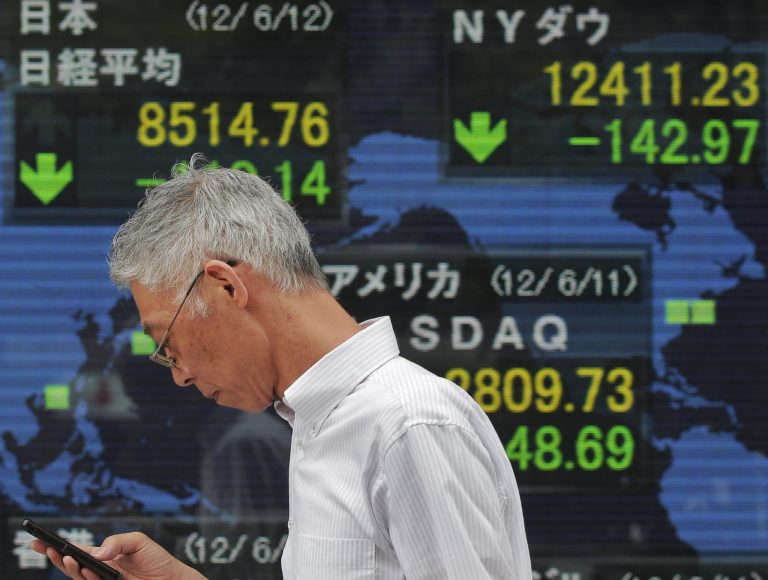   A man uses his mobile phone in front of the electronic stock board of a securities firm in Tokyo, Tuesday, June 12, 2012. Asian stock markets slid Tuesday as enthusiasm for a European plan to rescue Spain's teetering banks turned to skepticism. Japan's Nikkei 225 index fell 1.3 percent to 8,514.76. (AP Photo/Itsuo Inouye)  