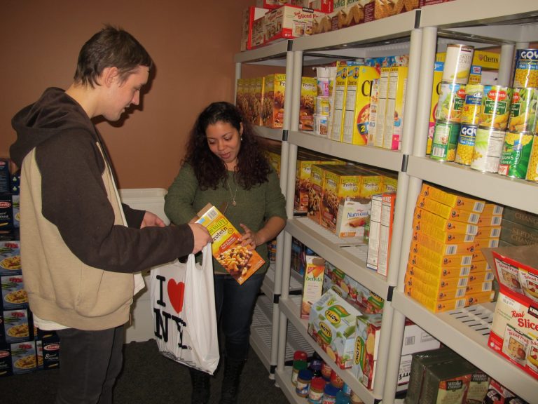 In this photo taken on Tuesday, March 4, 2014, at Stony Brook University,  students Ruby Escalera-Nater  and Will Addison fill a bag of food to give to guests at the college's recently opened food pantry. Officials say there are a growing number of food pantries opening on college campuses across the country to assist students contending with rising education costs.(AP Photo/Frank Eltman)