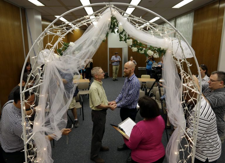 Bart Peterson, left, and Pete McNamara, center, are married by Marion County Clerk Beth White in Indianapolis on Wednesday. (AP/Michael Conroy)