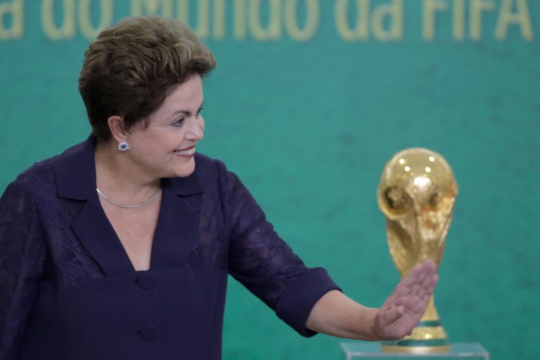 FILE - In this June 2, 2014, file photo, Brazil's President Dilma Rousseff waves to children at a ceremony where FIFA President Sepp Blatter presented the 2014 World Cup trophy to Rousseff at the Planalto presidential palace, in Brasilia, Brazil. President Rousseff has taken to the nation's airwaves Tuesday June 10, 2104, to deliver a pre-taped address trying to rally the nation behind the World Cup that begins this week. (AP Photo/Eraldo Peres,File)