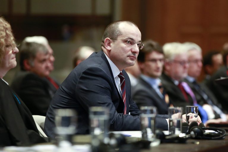 Croatian Minister Orsat Miljenic, center, awaits the start of public hearings at the International Court of Justice (ICJ) in The Hague,  Netherlands, Monday, March 3, 2014. Croatia is accusing Serbia of genocide during fighting in the early 1990's as the former Yugoslavia shattered in spasms of ethnic violence, in a case at the United Nations' highest court that highlights lingering animosity in the region. Croatia is asking the ICJ to declare that Serbia breached the 1948 Genocide Convention when forces from the former Federal Republic of Yugoslavia attempted to drive Croats out of large swaths of the country after Zagreb declared independence in 1991. (AP Photo/Jiri Buller)